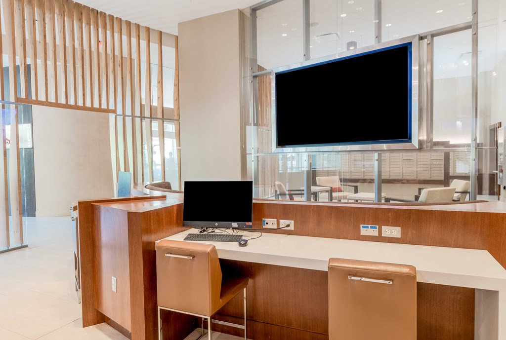 a desk with a computer and a monitor in a lobby